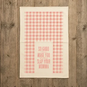 Full cream cotton kitchen towel with coral red gingham pattern and So Good It’ll Make You Wanna Slap Your Momma saying