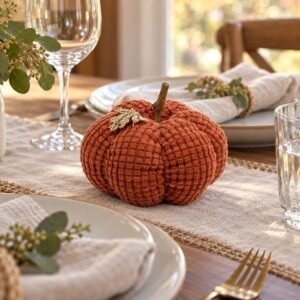 Small burnt-orange waffle-weave pumpkin on a Thanksgiving table beside linen napkins and place settings.