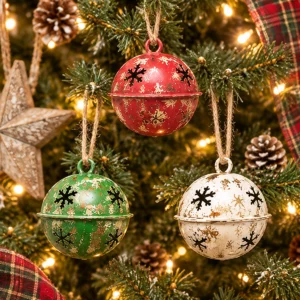 Red green and white distressed snowflake jingle bells hanging on a decorated Christmas tree